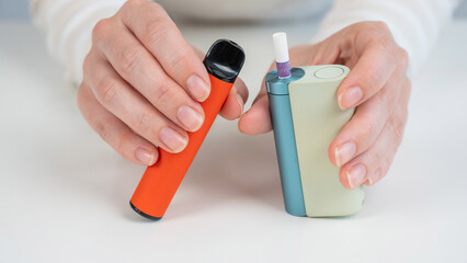 Woman holding regular, electronic cigarette and disposable vape on white background. Tobacco...