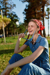 Lifestyle woman in modern boho-western denim street style laughing outdoors on sunny day, holding...