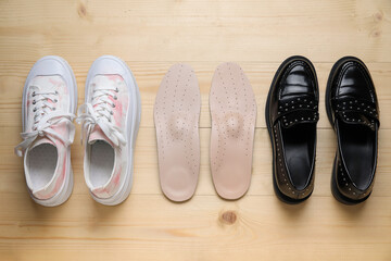 Stylish female shoes and orthopedic insoles on wooden background