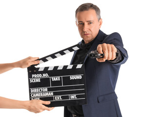 Mature actor holding gun and hands with clapperboard on white background