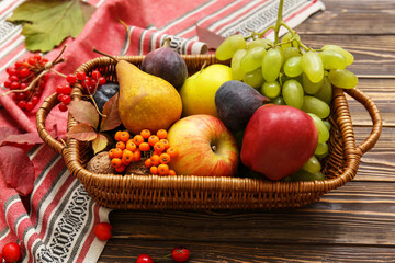 Wicker basket with different fresh fruits on wooden background