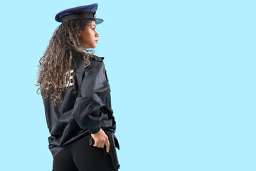 African-American female police officer with gun on blue background