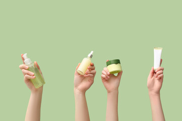 Female hands with different cosmetic products on green background