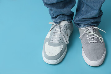 Legs of young man in different stylish sneakers on blue background
