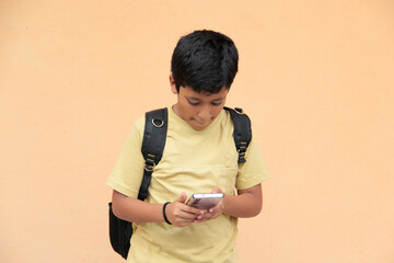 A 10-year-old Latino boy uses his cell phone to play video games, make video calls, send messages,...