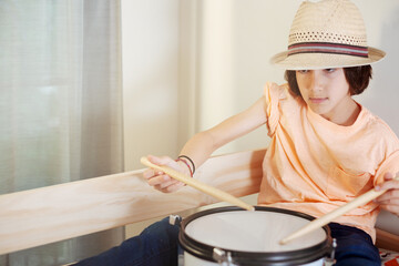 Boy focused on playing snare drum in natural light