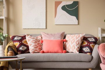 Interior of living room with cozy sofa, pillows, pictures and coffee table