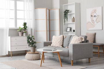 Light living room with folding screen, comfortable sofa, coffee table and chest of drawers