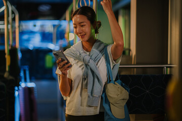 Young woman using smartphone on night bus ride home