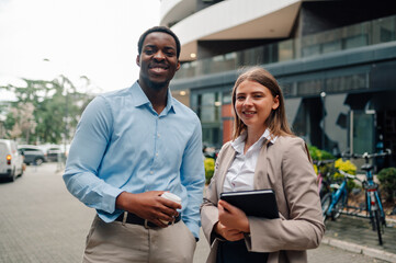 Smiling business people holding coffee and tablet in urban setting