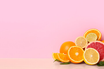 Different cut citrus fruits and mint leaves on color background