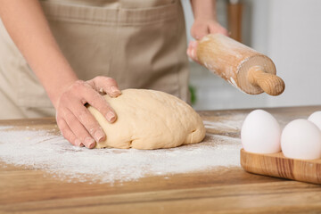 Woman rolling out fresh dough in kitchen