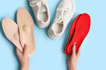 Woman with orthopedic insoles and sneakers on blue background
