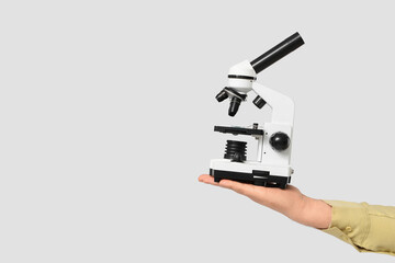 Male hand holding microscope on grey background