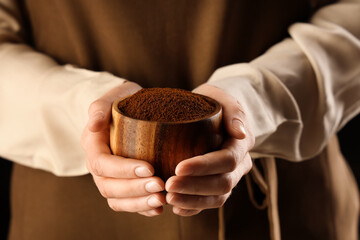 Female barista holding wooden bowl with coffee powder, closeup