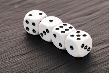 4 white dice with black dots in a row on a dark table