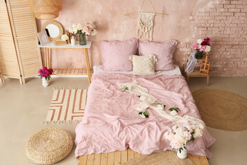 Interior of stylish bedroom with cozy bed and beautiful peonies
