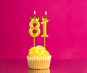 Birthday celebration with number 81 candle - Yellow cupcake on a pink background