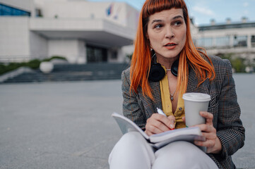 Journalist writing notes while drinking coffee outdoors