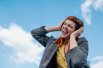 Young woman singing with headphones under blue sky