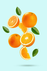  Falling orange with cut in half and leaves isolated on light green background.
