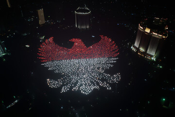 Drone formation forming Garuda Pancasila in red and white lights, captured at night above Jakarta skyline, ideal for Indonesian Independence Day themes and patriotic celebration visuals.