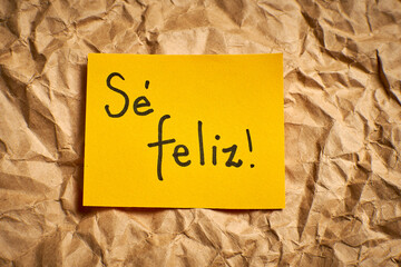 Handwritten Spanish phrase Be happy on colorful background