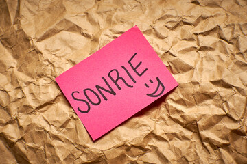 Simple handwritten Spanish message Smile on bright paper