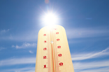 High temperature on thermometer against blue sky on sunny day. Summer weather
