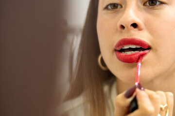 Woman applying red lipstick getting ready for night out