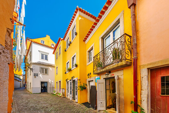 The Beco do Forno do Castelo, a narrow cobblestone street of colorful buildings with shops in the Bairro do Castelo Castle of St George area of the Alfama district, Lisbon Portugal.