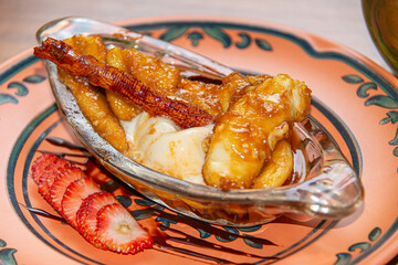 Flambéed Banana with Vanilla Ice Cream on Glass Plate in Colonial Restaurant