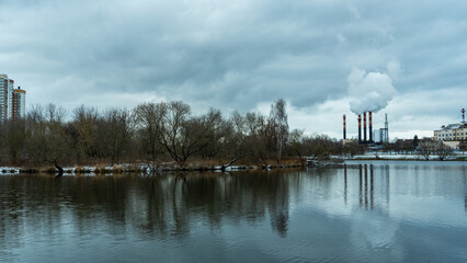 Industrial chimneys emit thick smoke into the winter sky, highlighting urban air pollution. A...