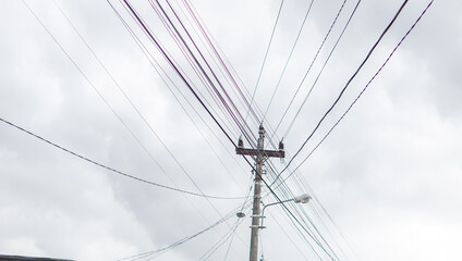 Power lines converge above on utility pole reaching skyward, generating a sense of connection.