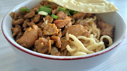 Savory Chicken Noodles. Close-up of Mie Ayam, Indonesian chicken noodles, featuring tender chicken, savory sauce, and a crispy wonton cracker. A satisfying meal