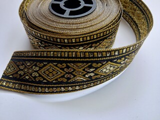 Golden colored rolled ribbon with ethnic design isolated with white background.
