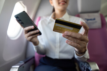 Payment Experience. Female traveler using credit card and smartphone on flight.