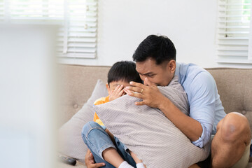 Scared Child Comforted by Father. A father and son share a tense moment while watching a scary...