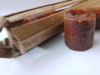 Brown sugar or palm sugar or gula Jawa wrapped in leaves  placed on White background.