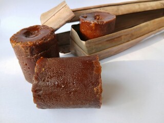 Brown sugar or palm sugar or gula Jawa wrapped in leaves  placed on White background.
