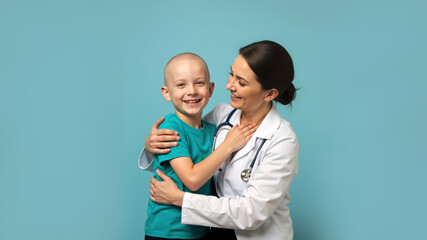 Smiling bald boy with a female doctor on a blue background. Happy child cancer patient and oncologist. Pediatric care and hope concept.