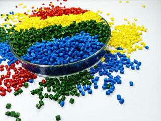 various colors of masterbatch granules in glass containers, polymer carrying resin and pigments poured in white background, suitable for product catalog design of industrial plastic company profile