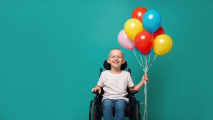 Happy bald boy in wheelchair with balloons on teal background. Smiling child cancer patient celebrating recovery. Hope concept with copy space.