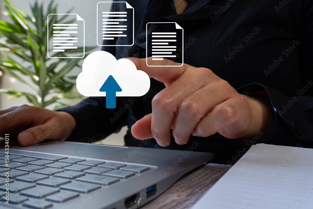 Poster businesswoman in front of a computer pointing at a cloud icon with a blue arrow and some documents. 