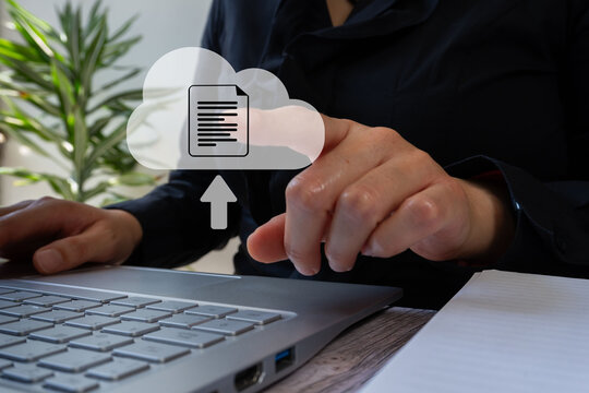 Businesswoman in front of a computer pointing at a cloud icon with a document and arrow,  concept of uploading documents to the cloud as a backup