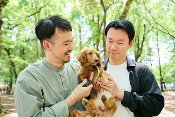公園で犬を抱える男性2人