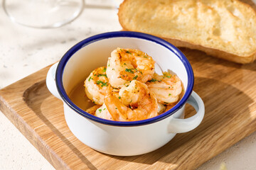 Shrimp with garlic in bright rustic lighting, overhead composition, served with toasted ciabatta