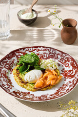 Zucchini draniki with salmon and poached egg, bright daylight, overhead ceramic plate composition