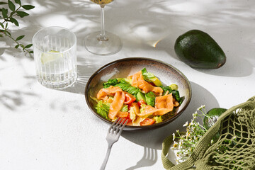 Salmon and avocado salad, bright daylight, overhead composition on textured white surface