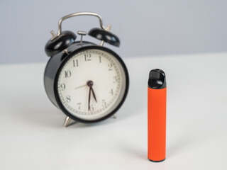Disposable vape and alarm clock on white background. 